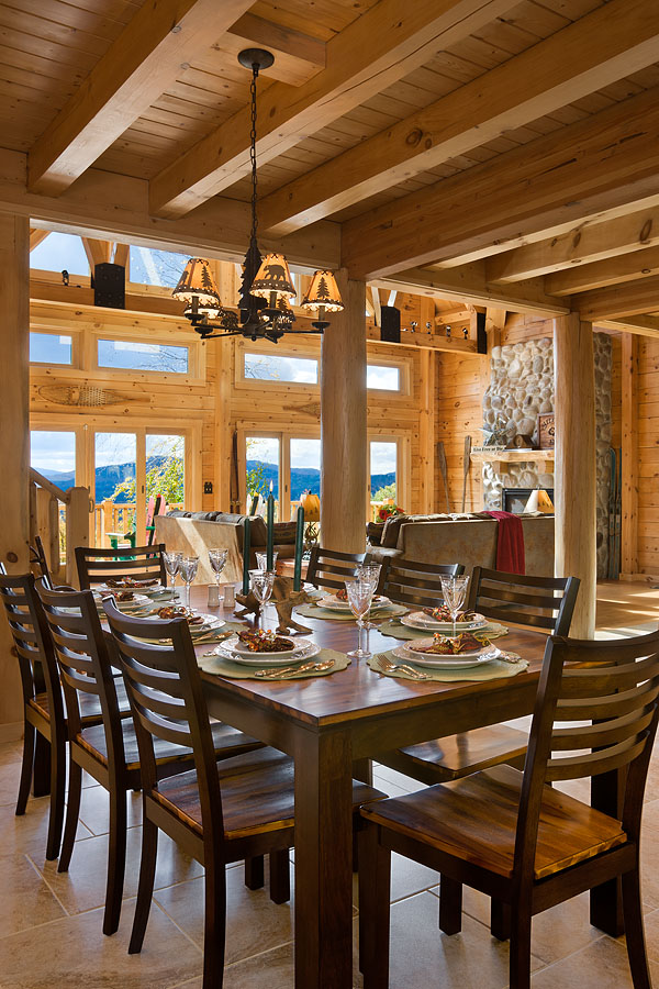 Interior, vertical, dining room toward living room and windows with mountain view, Rosenfeld residence, Franconia, New Hampshire; Coventry Log Homes